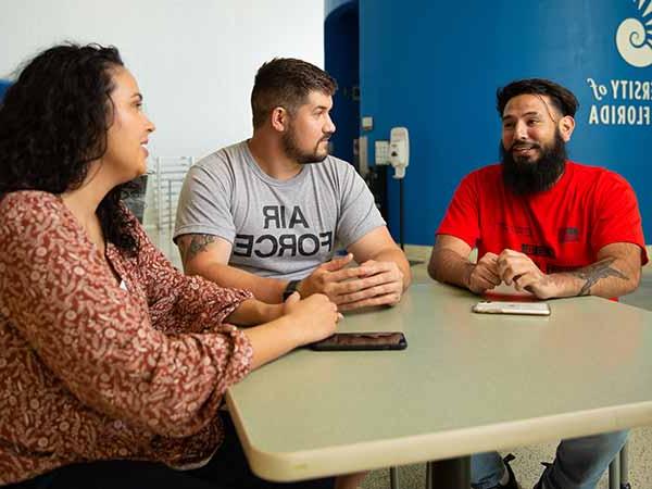 三个学生在HLS设施的一张桌子旁聊天